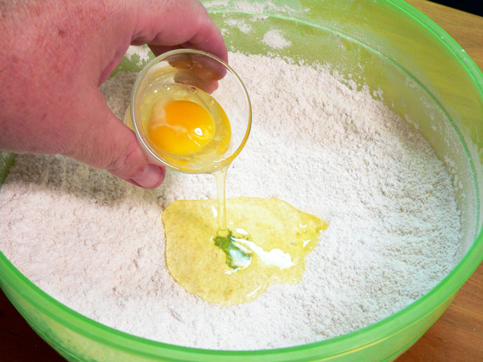 Add one whole egg into the well you created in the flour.