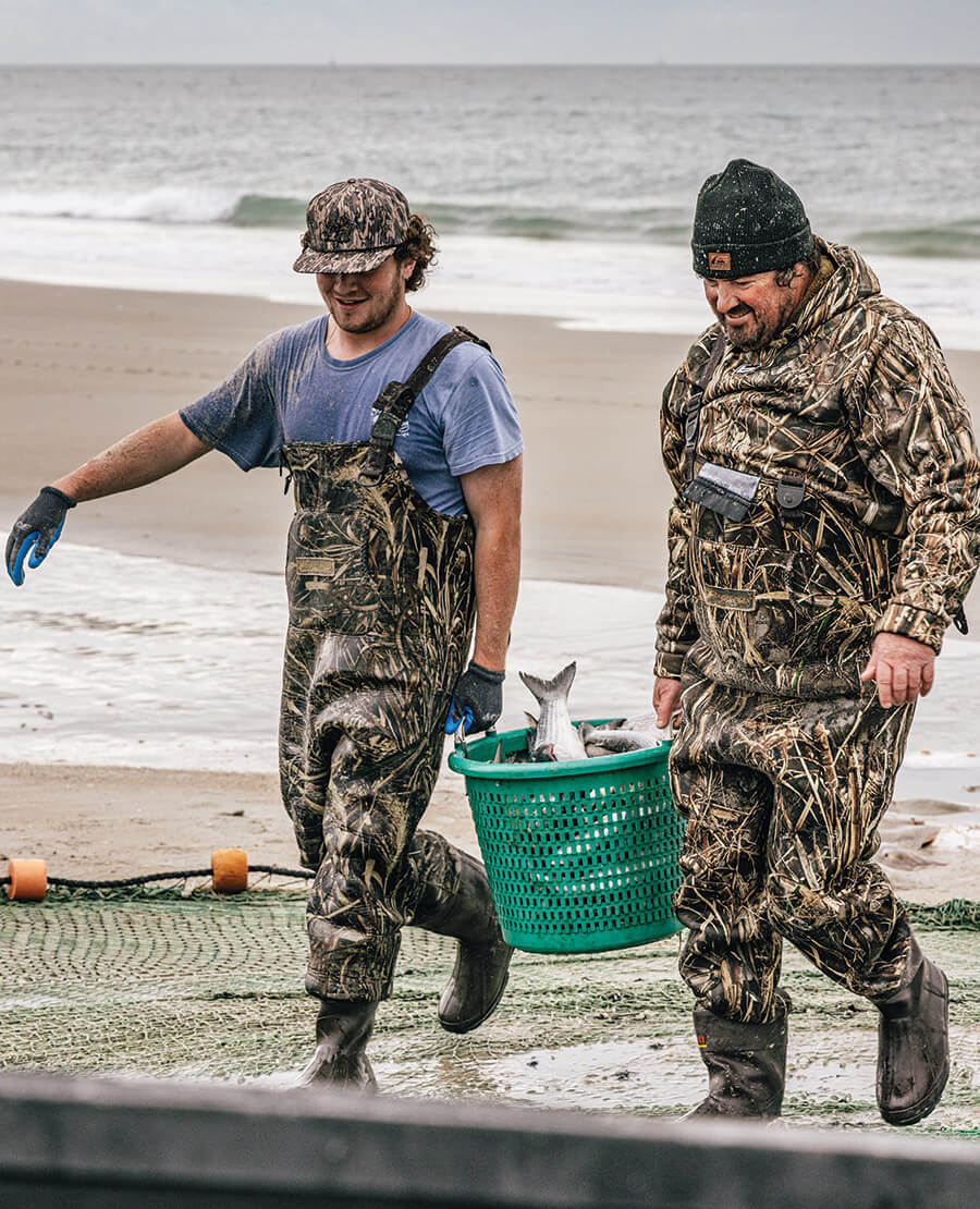 Fishermen carrying baskets of mullet