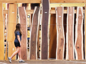 Woman walks among planks of wood at the Hardware Store of North Carolina