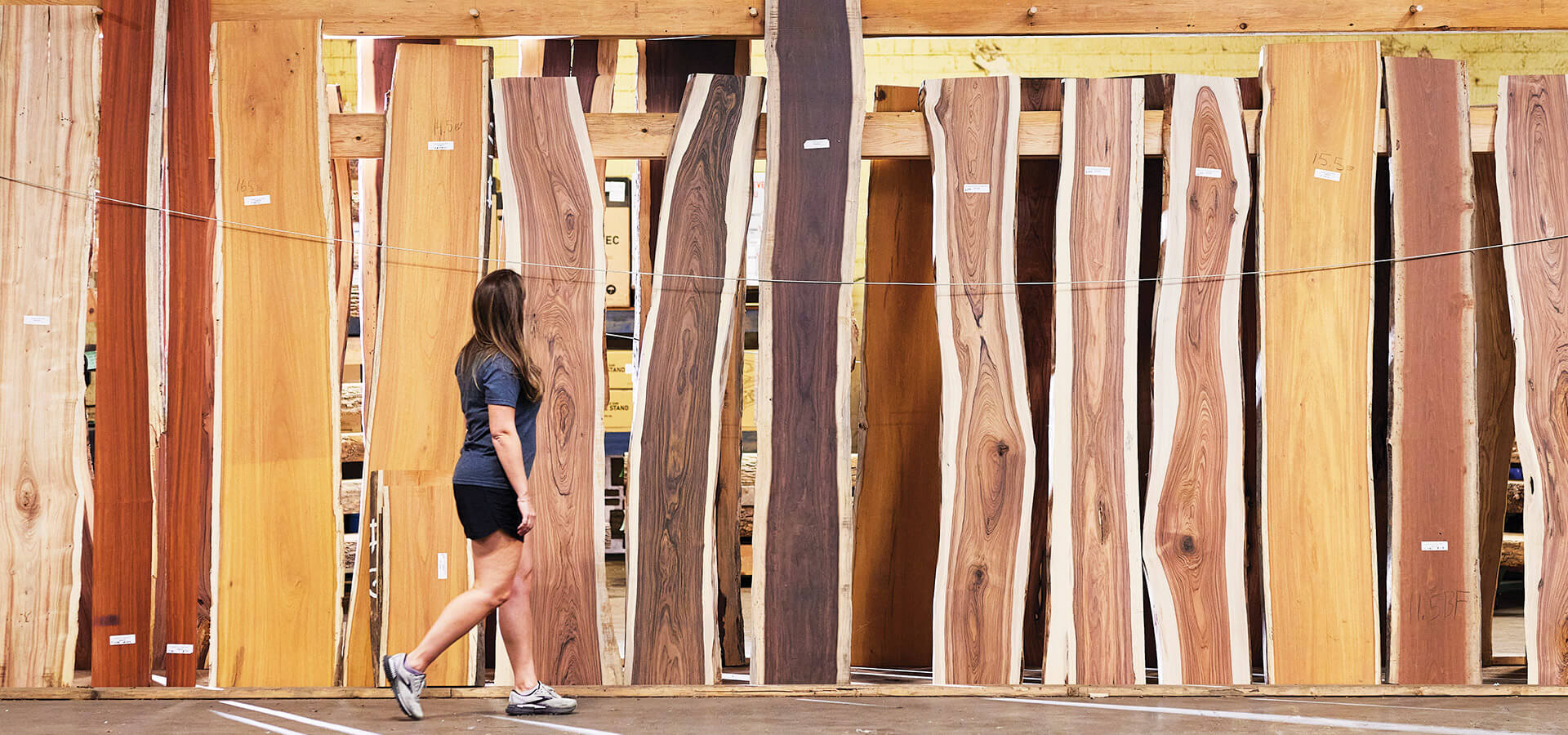 Woman walks among planks of wood at the Hardware Store of North Carolina