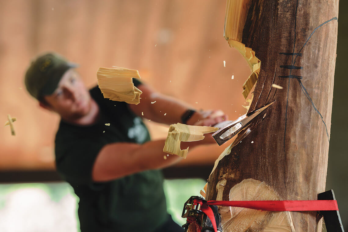 Grayson Smith cuts down a tree with an axe