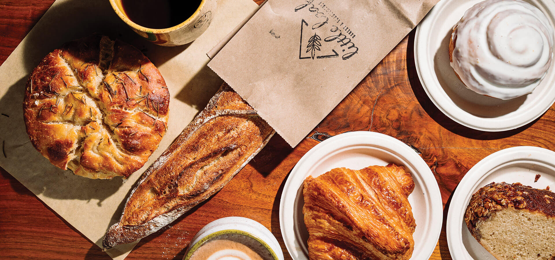 Table with focaccia, baguette, croissant, and cinnamon bun at Little Loaf.